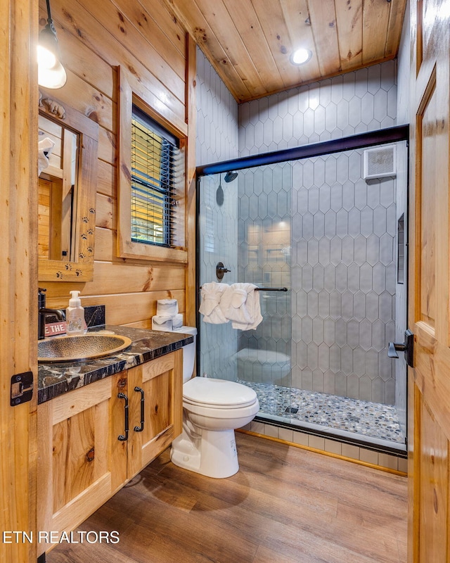 bathroom with toilet, a stall shower, and wood finished floors