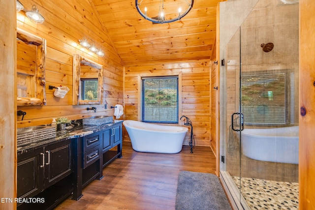 full bathroom featuring double vanity, wood finished floors, vaulted ceiling, wood walls, and a shower stall