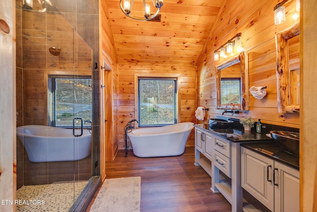 full bath featuring a stall shower, lofted ceiling, wood finished floors, vanity, and wood walls