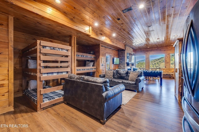 living room with wooden ceiling, wood walls, and wood finished floors