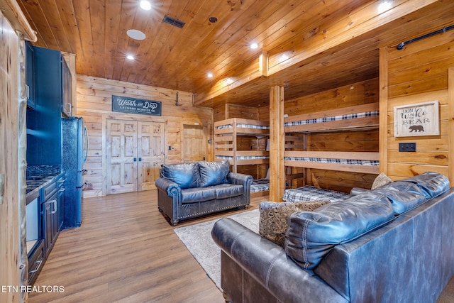 living area with light wood-type flooring, wood ceiling, wooden walls, and visible vents