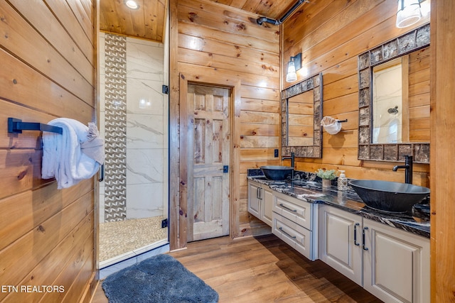 bathroom featuring double vanity, a sink, wooden walls, and wood finished floors