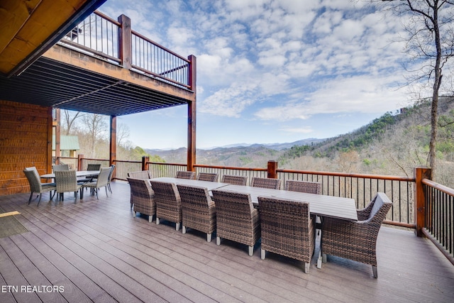 wooden terrace with outdoor dining space and a mountain view