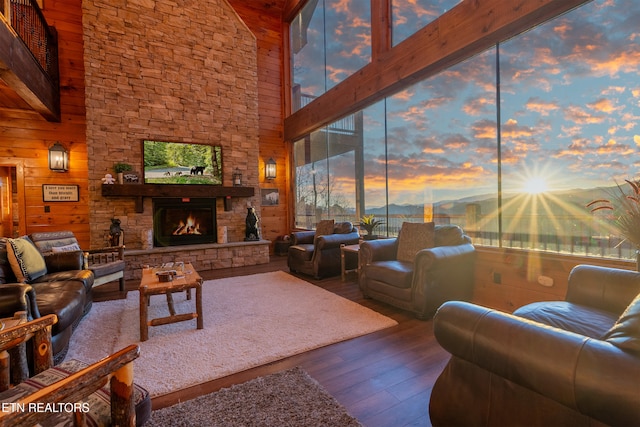 living area featuring a stone fireplace, wood finished floors, and wooden walls