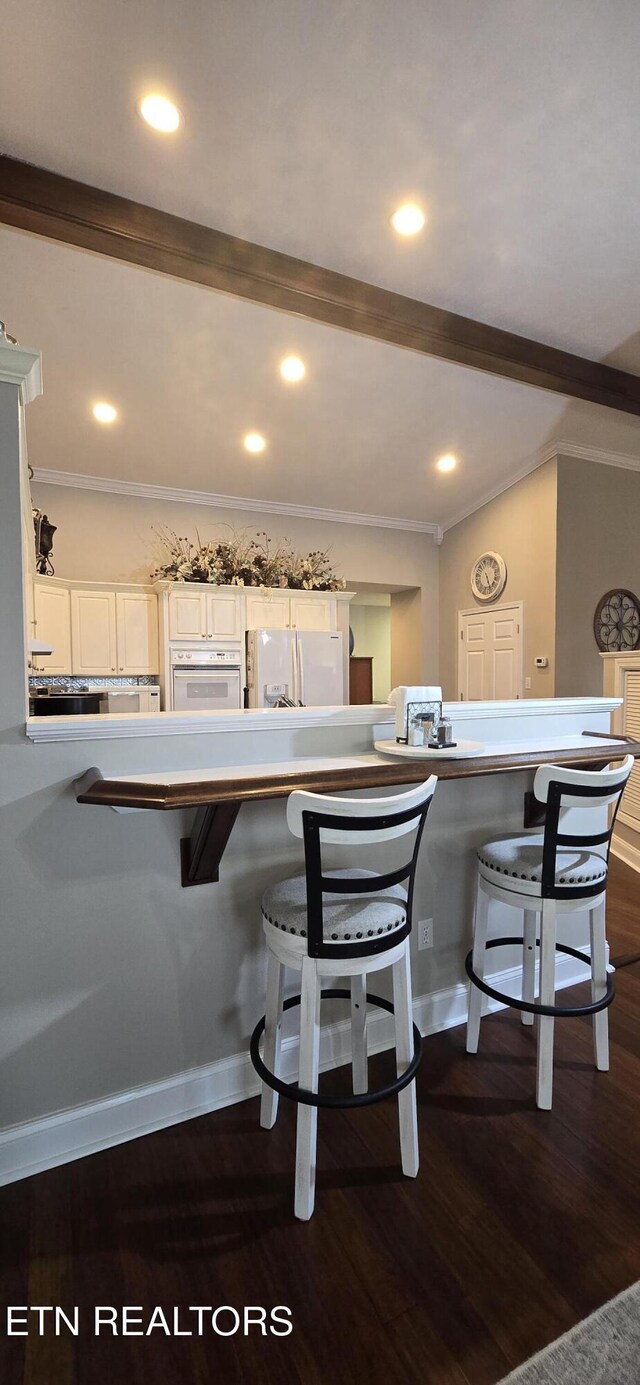 353 Southshore Dr, Greenback, TN 37742 - kitchen featuring ornamental molding, a kitchen bar, white appliances, dark wood finished floors, and white cabinets