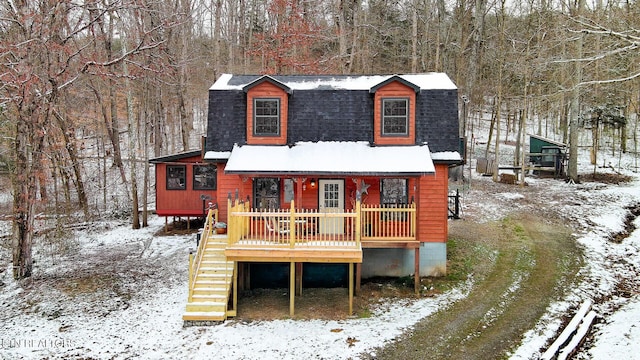 exterior space featuring stairs, a shingled roof, and a view of trees