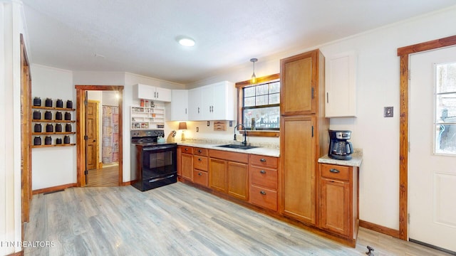 kitchen featuring black electric range, brown cabinets, a sink, and light wood finished floors