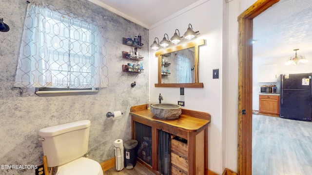 bathroom featuring toilet, wood finished floors, vanity, ornamental molding, and an inviting chandelier