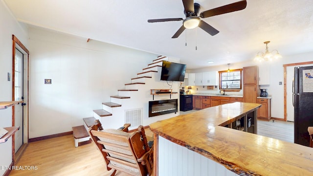 kitchen with visible vents, light wood-style floors, decorative light fixtures, light countertops, and black appliances