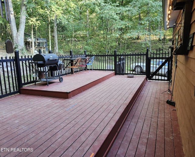 wooden terrace featuring grilling area and a wooded view