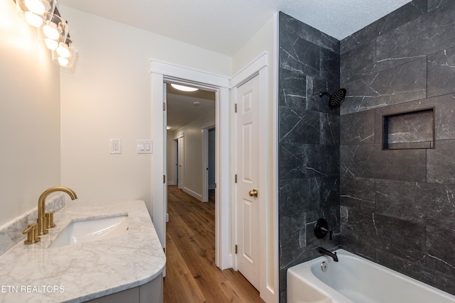 full bathroom with shower / bath combination, vanity, a textured ceiling, and wood finished floors