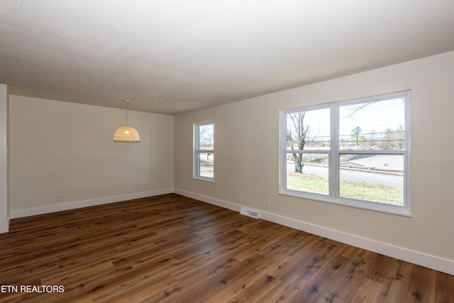 unfurnished room featuring visible vents, dark wood finished floors, and baseboards