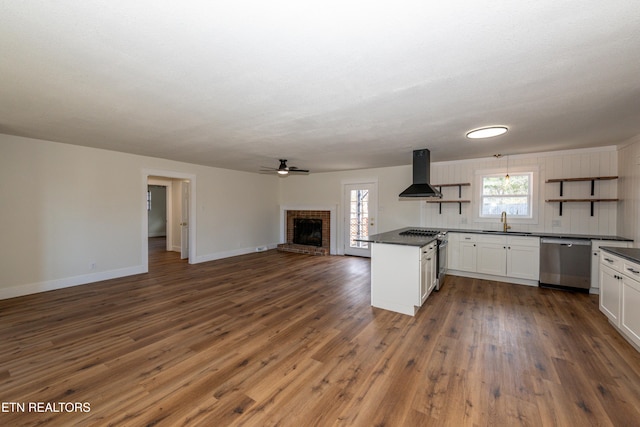 kitchen with stainless steel appliances, open floor plan, range hood, open shelves, and dark countertops