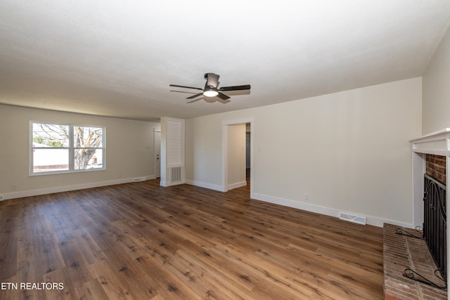 unfurnished living room featuring visible vents, a fireplace, baseboards, and wood finished floors