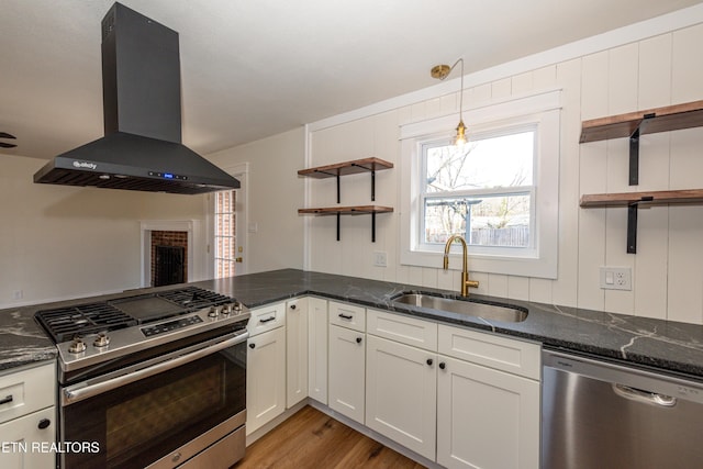 kitchen with range hood, open shelves, stainless steel appliances, a sink, and dark stone counters