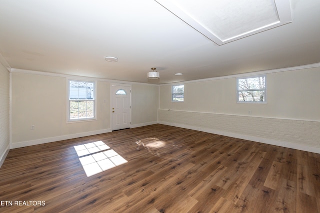 interior space with a wealth of natural light, ornamental molding, and dark wood-style flooring