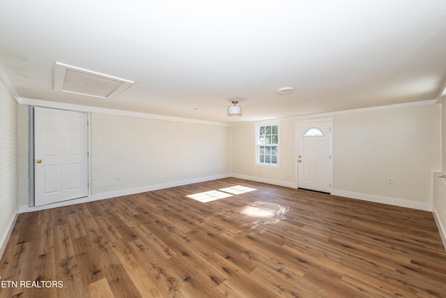 spare room with brick wall, wood finished floors, and crown molding