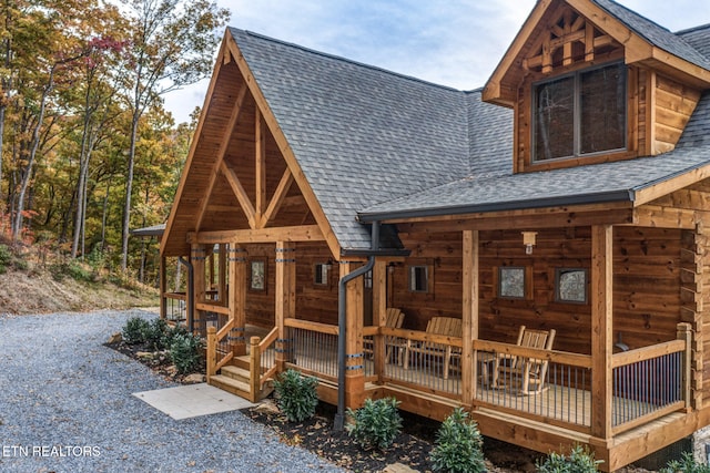 exterior space with a porch and roof with shingles