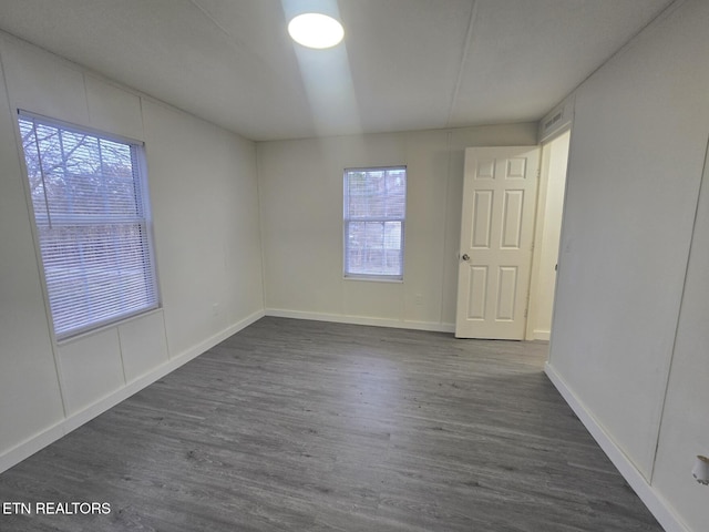 spare room featuring dark wood-type flooring and baseboards