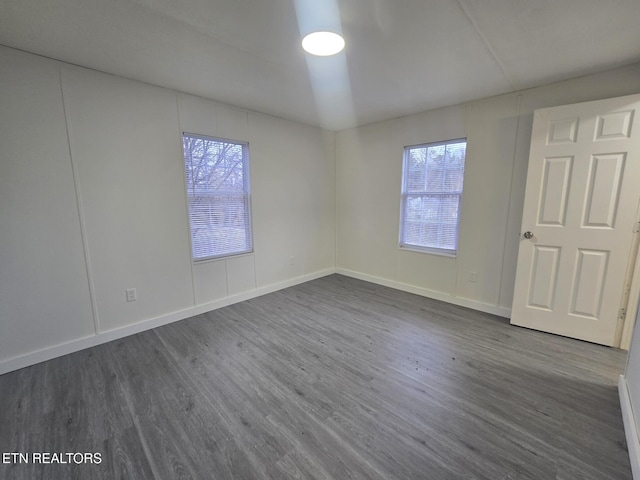 spare room with plenty of natural light, baseboards, and dark wood-type flooring