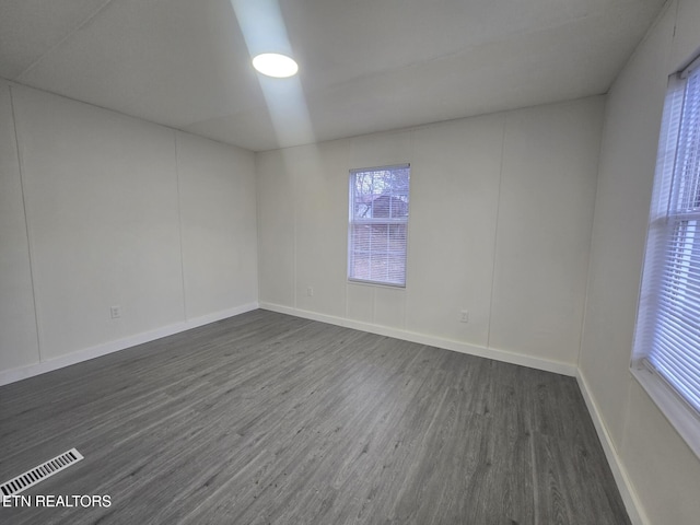 spare room featuring visible vents, dark wood finished floors, and baseboards