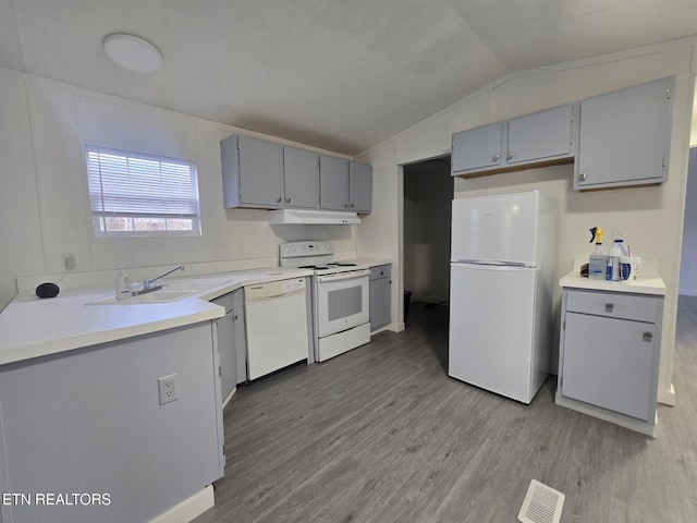 kitchen with lofted ceiling, light countertops, a sink, white appliances, and under cabinet range hood