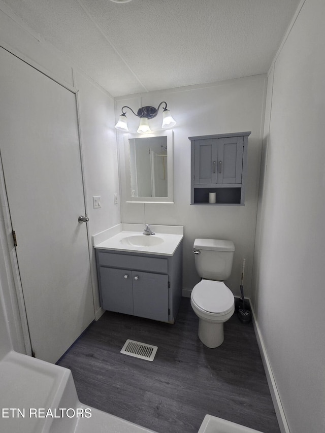bathroom with visible vents, toilet, wood finished floors, a textured ceiling, and vanity