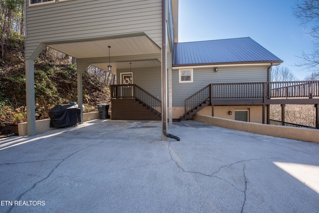 exterior space featuring aphalt driveway, stairway, metal roof, and a carport