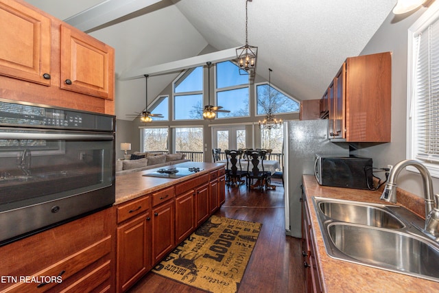 kitchen featuring dark wood-style floors, black electric stovetop, light countertops, wall oven, and a sink