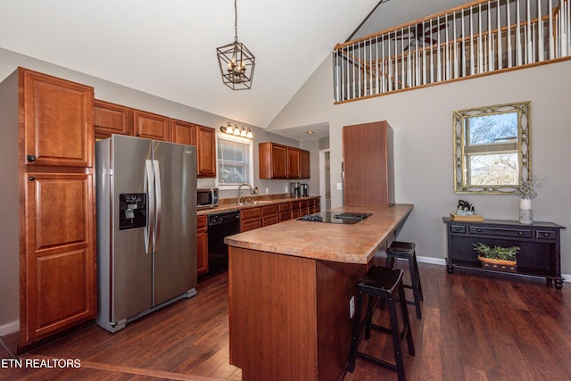 kitchen featuring dark wood finished floors, a breakfast bar area, a healthy amount of sunlight, a sink, and black appliances