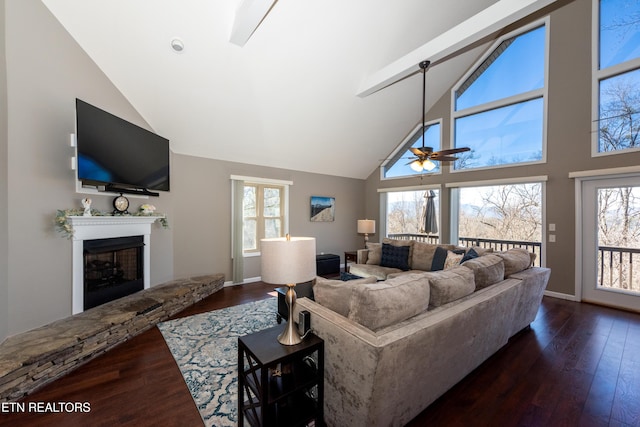 living area featuring a fireplace with raised hearth, dark wood-style flooring, plenty of natural light, and lofted ceiling