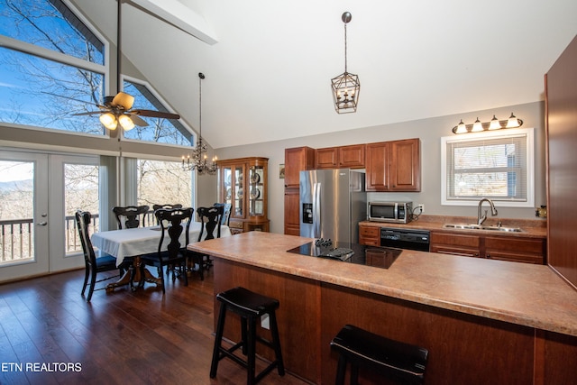 kitchen featuring dark wood-style flooring, a breakfast bar area, brown cabinetry, a sink, and black appliances