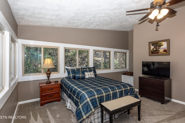 carpeted bedroom featuring a textured ceiling, a ceiling fan, and baseboards