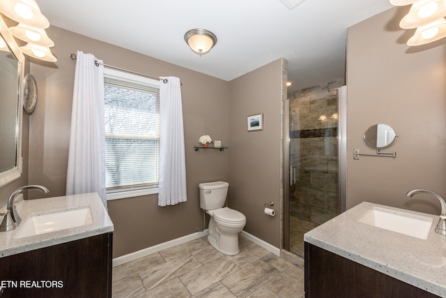 bathroom with toilet, a shower stall, vanity, and baseboards