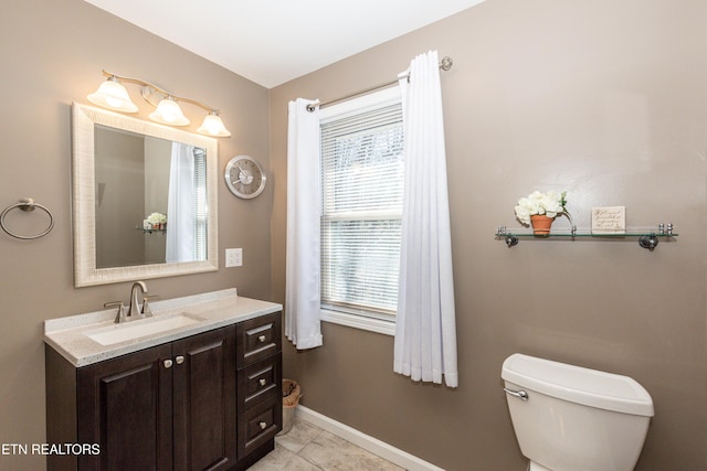 bathroom featuring toilet, vanity, baseboards, and tile patterned floors