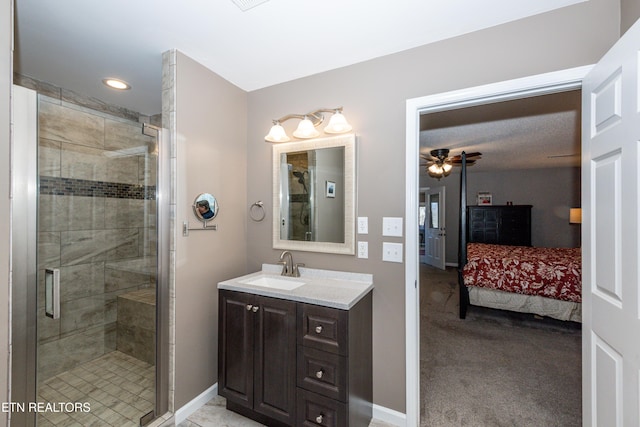 ensuite bathroom with ensuite bathroom, a stall shower, ceiling fan, vanity, and baseboards