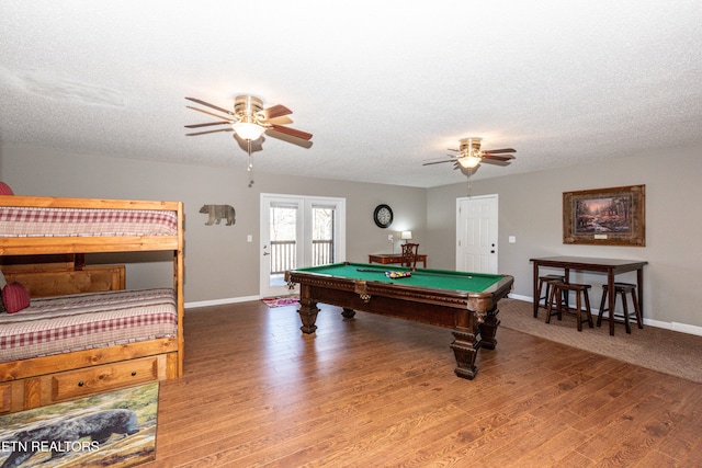 recreation room featuring ceiling fan, a textured ceiling, wood finished floors, and baseboards