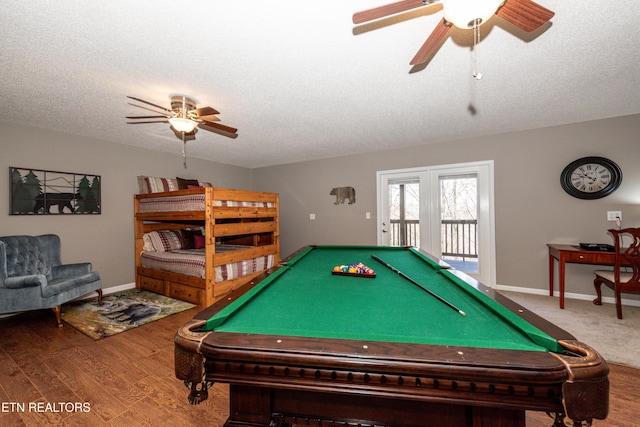 recreation room featuring a ceiling fan, a textured ceiling, baseboards, and wood finished floors