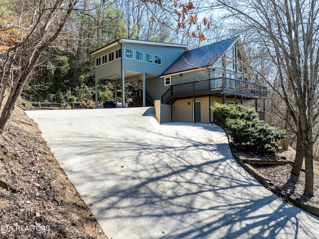 view of front of property featuring stairs, a carport, aphalt driveway, and metal roof