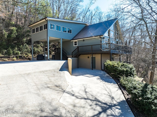 view of front facade featuring metal roof, a carport, stairway, and concrete driveway