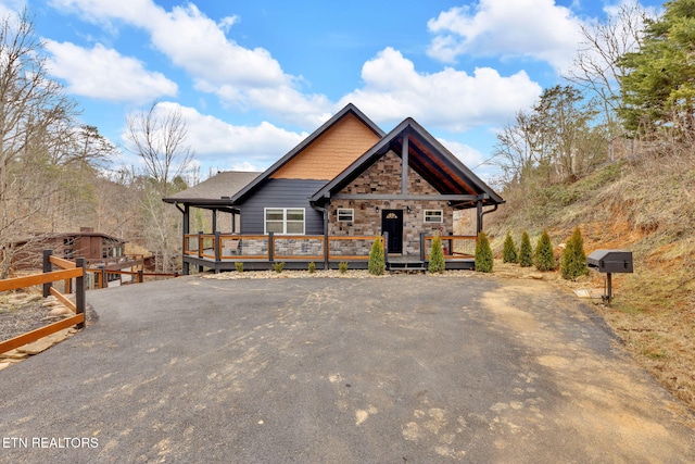 chalet / cabin featuring stone siding, driveway, and a wooden deck