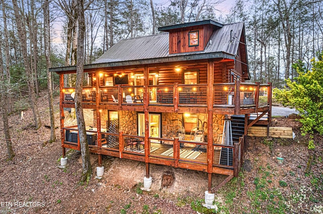 back of property featuring stone siding, stairs, metal roof, and a deck