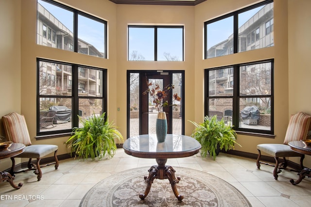 interior space featuring light tile patterned floors, a high ceiling, and baseboards