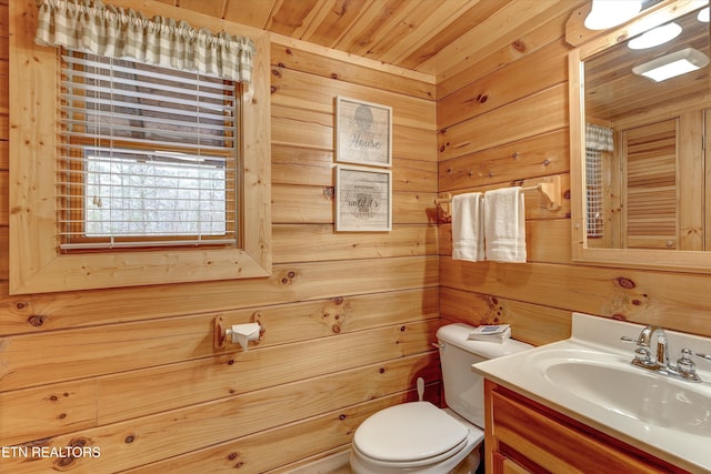 half bathroom with toilet, wood ceiling, wooden walls, and vanity