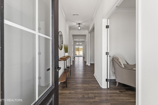 corridor with baseboards, visible vents, dark wood-style flooring, crown molding, and a chandelier