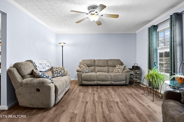 living area featuring ceiling fan, a textured ceiling, baseboards, light wood-style floors, and ornamental molding