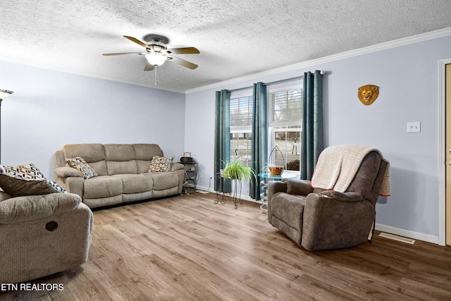 living area with baseboards, ceiling fan, wood finished floors, a textured ceiling, and crown molding