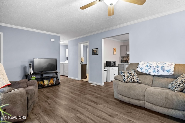 living area with a textured ceiling, baseboards, dark wood-style flooring, and washing machine and clothes dryer