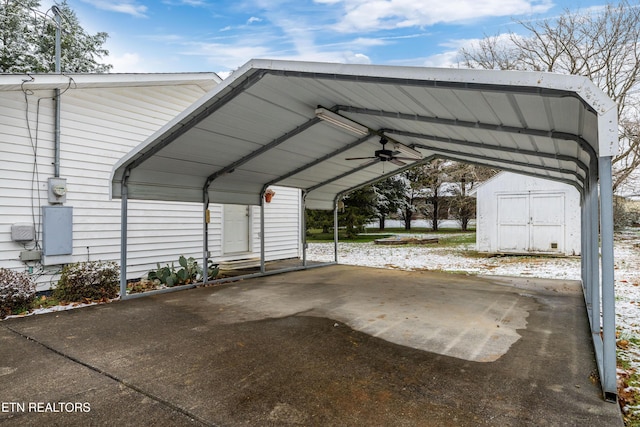 view of vehicle parking with a detached carport, ceiling fan, and a storage shed