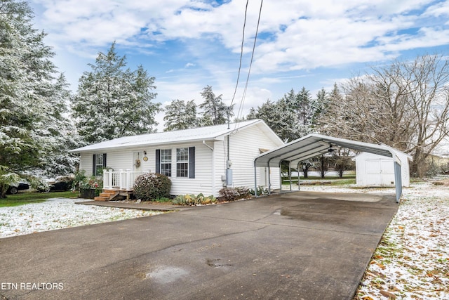 view of front facade with a storage shed, driveway, an outdoor structure, and a detached carport